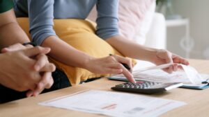 hands typing on calculator with paperwork on table