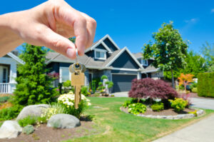 hand holding keys with a large home in background