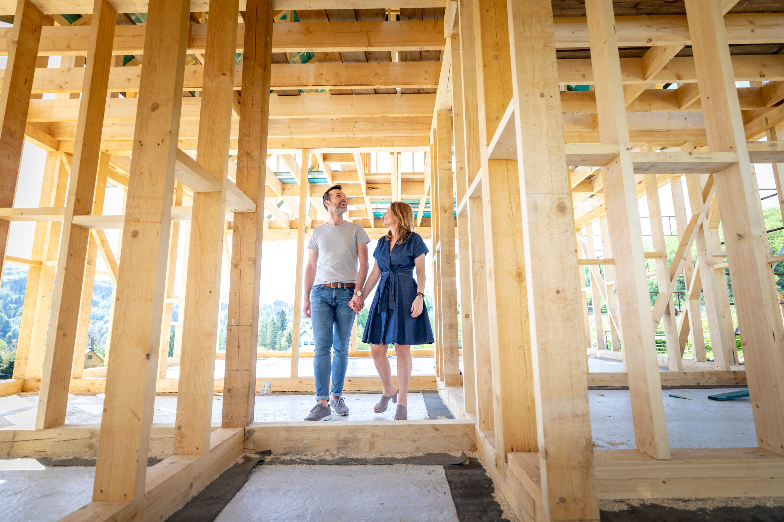 couple holding hands walking through construction of their home