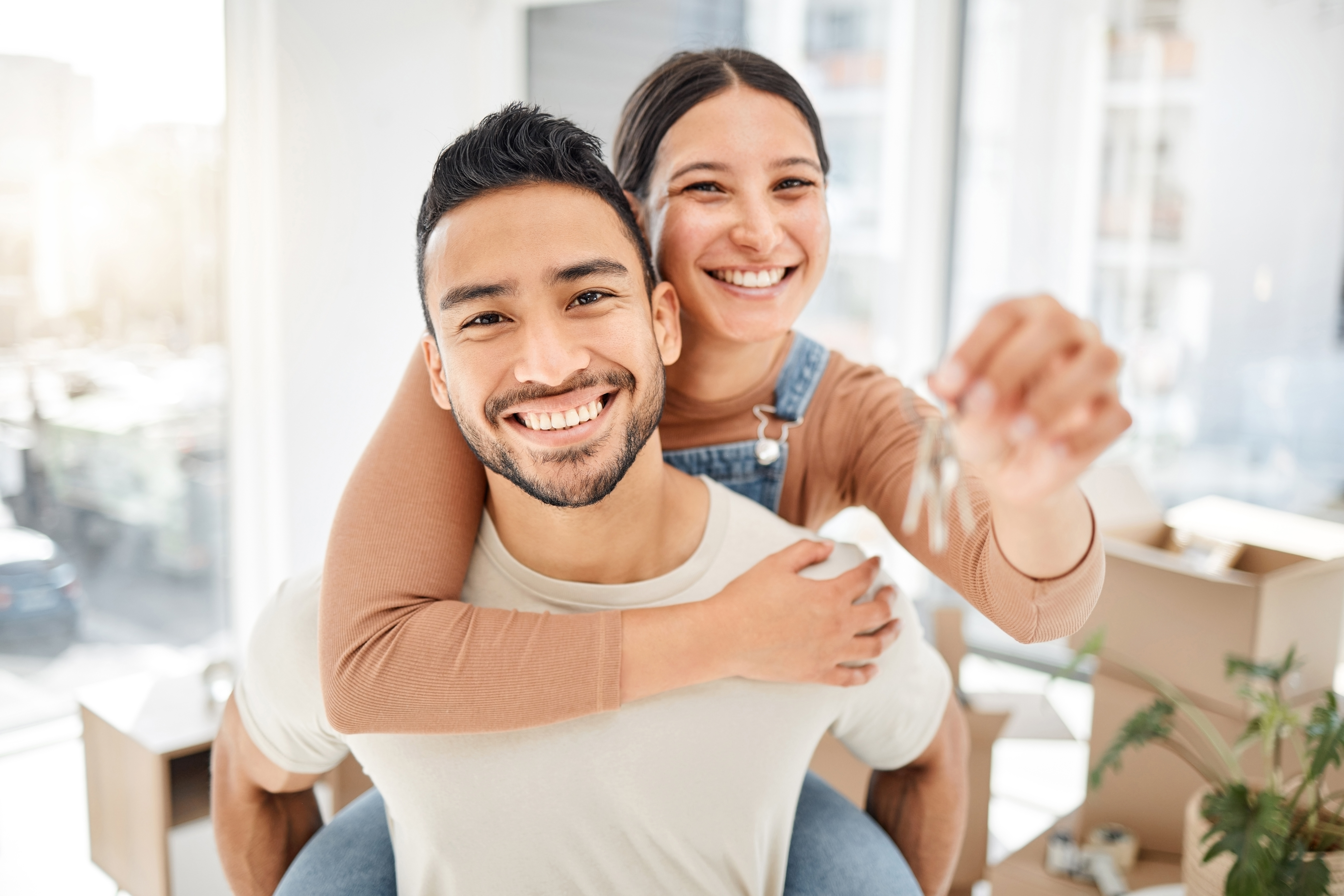 happy couple in piggy back with keys to a new home