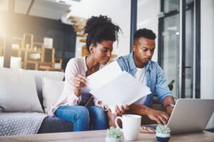 couple on sofa with laptop and paperwork