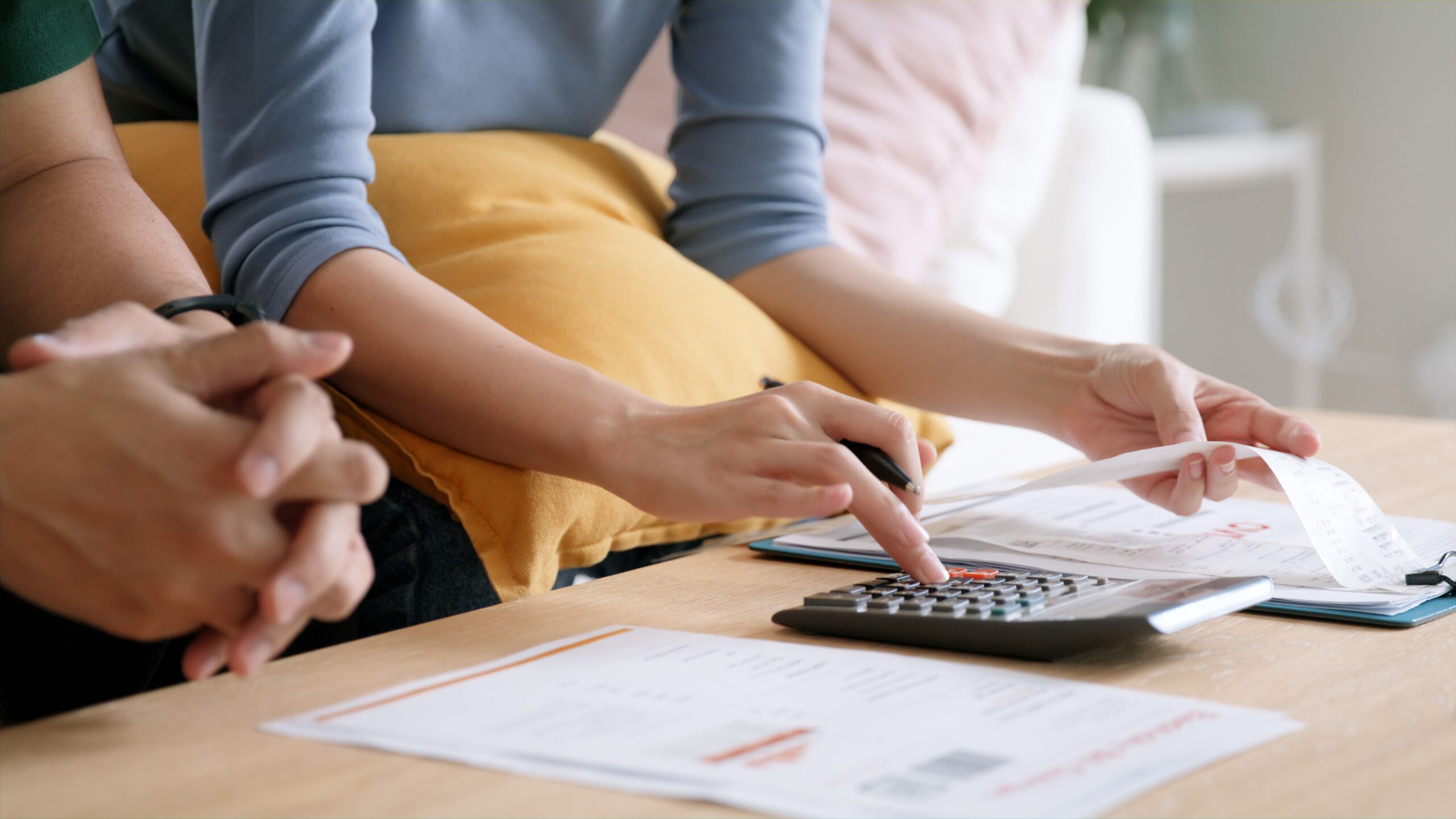 hands typing on calculator with paperwork on table