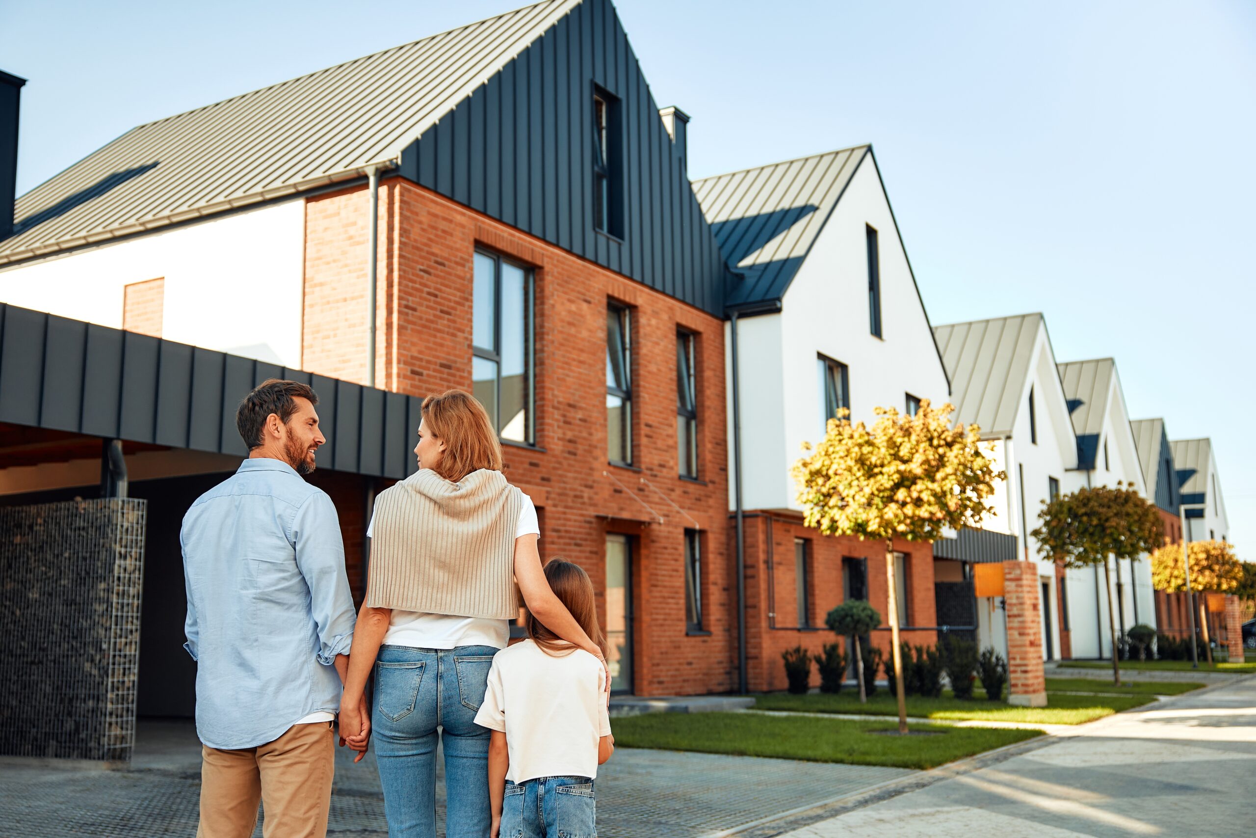 young happy family with a child looking at home from outside