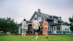 real estate agent showing a big blue home to young couple