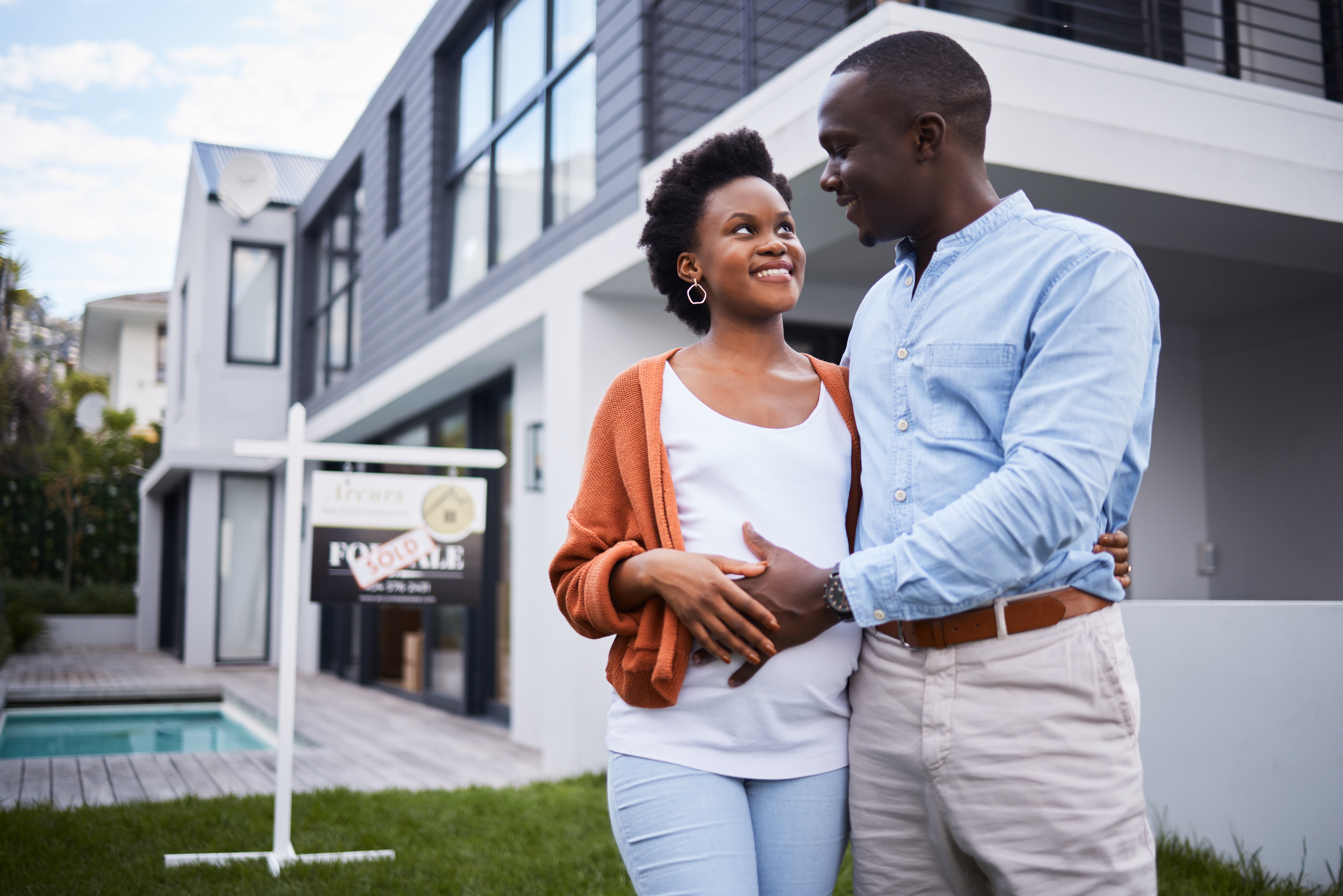 happy black couple standing outside of new home