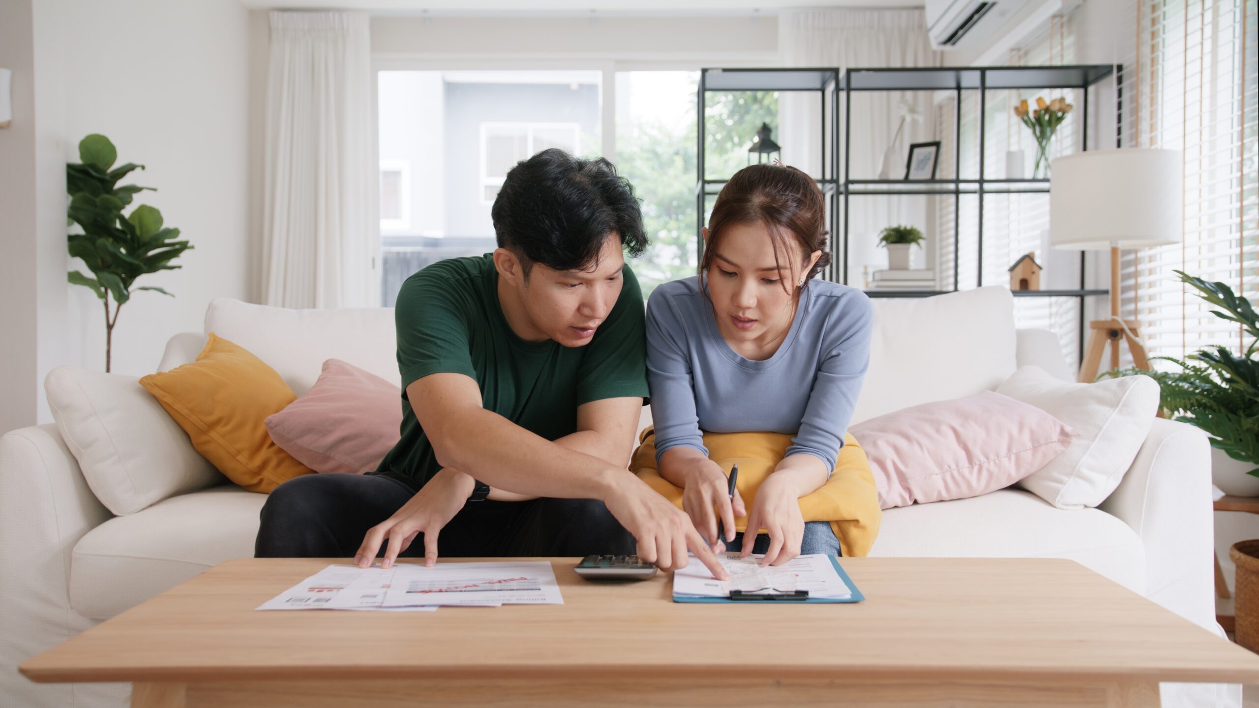 asian couple on couch looking at documents