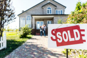 family standing outside of house with a sold sign
